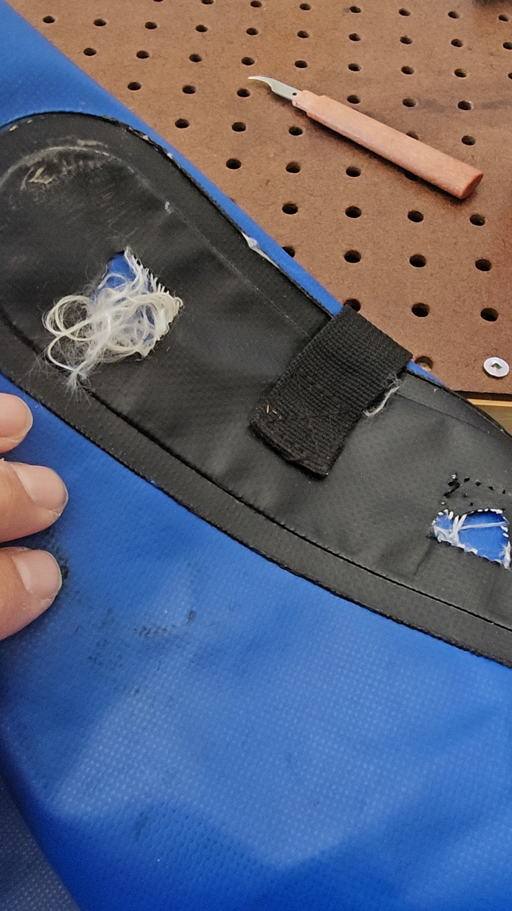 Zone déchirée avec anciennes coutures visibles sur sac étanche bleu