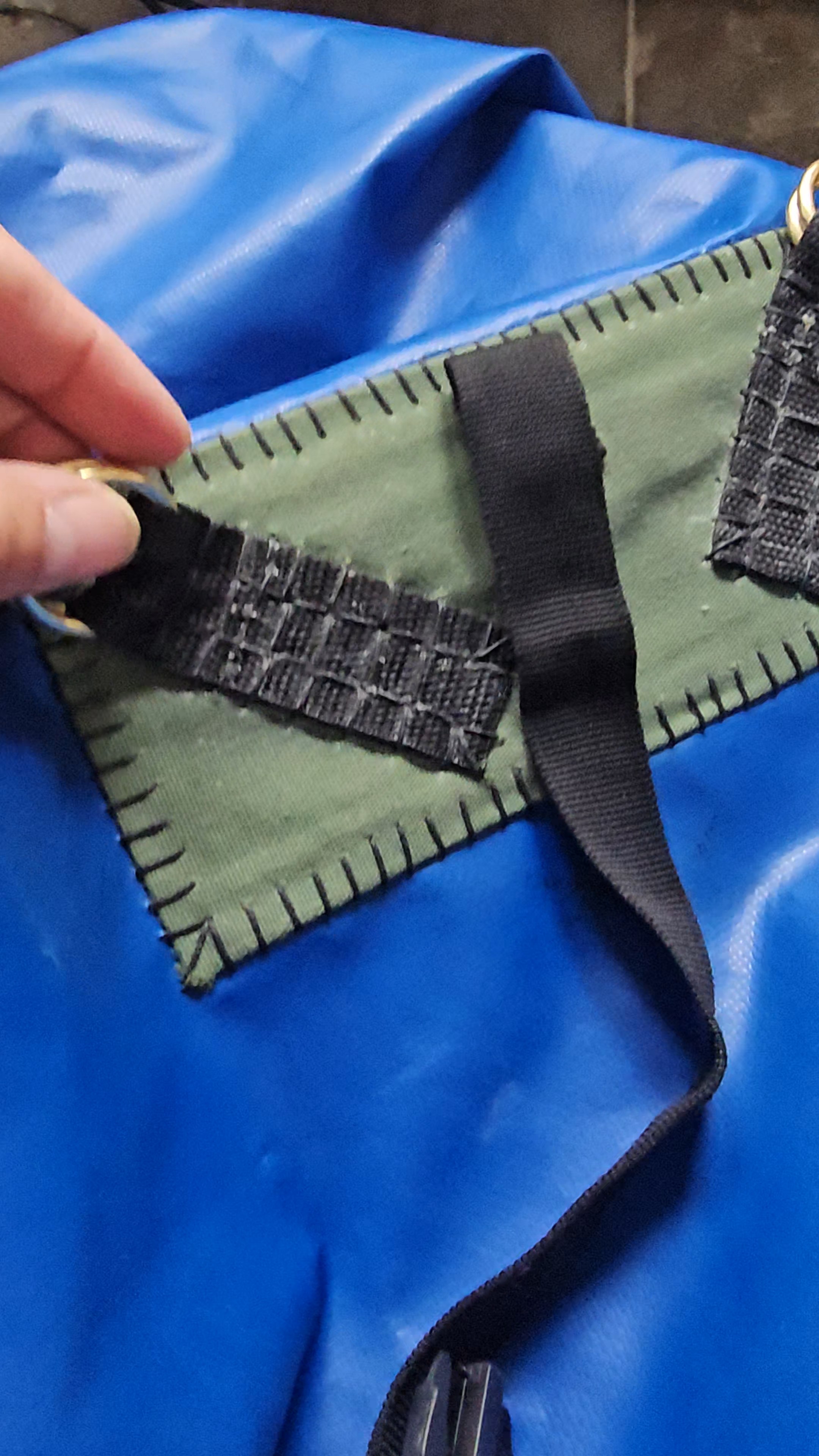 Sangle noire cousue sur tissu vert avec fond de bâche bleue